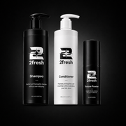 Three 2fresh haircare bottles on a black background: a tall black pump bottle of Shampoo, a tall white pump bottle of Conditioner, and a smaller black cylindrical bottle of Texture Powder.