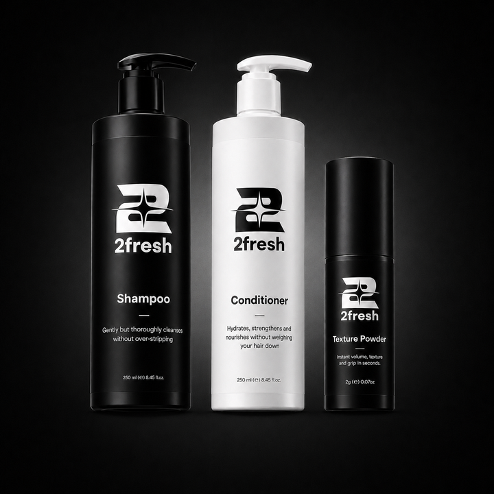 Three 2fresh haircare bottles on a black background: a tall black pump bottle of Shampoo, a tall white pump bottle of Conditioner, and a smaller black cylindrical bottle of Texture Powder.